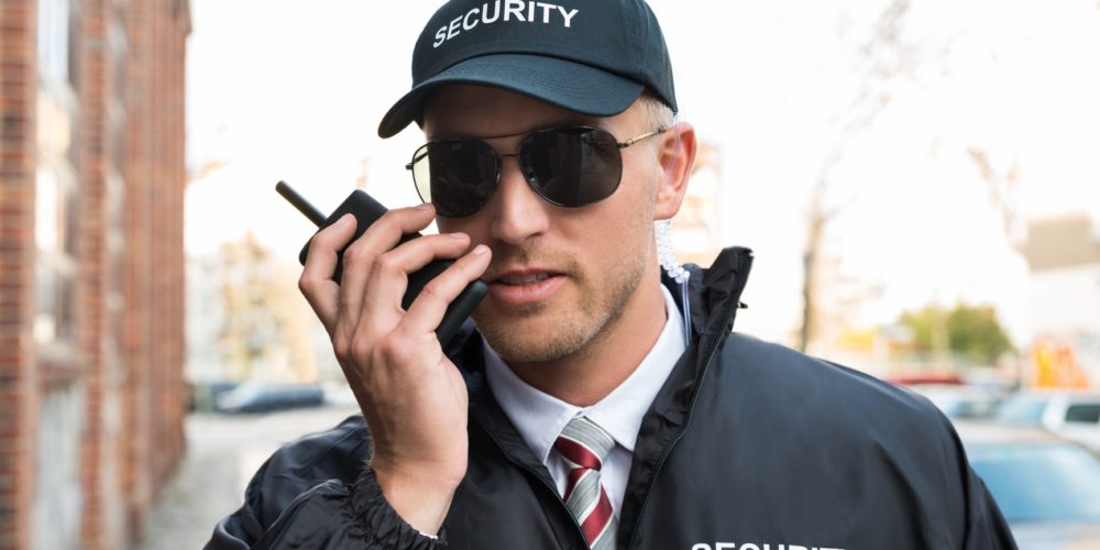Portrait Of Young Male Security Guard Talking On Walkie-talkie